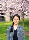 Headshot of Christine smiling in front of pink flowers